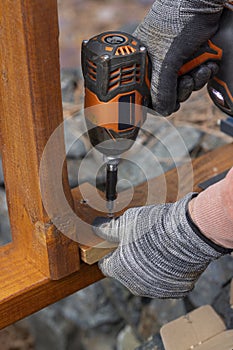 Contractor hanyman using tools to buildi a horizontal fence made from stained cedar