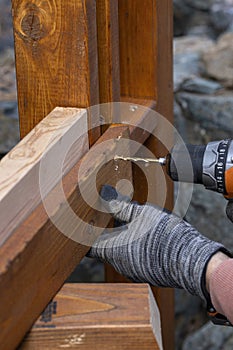 Contractor hanyman using tools to buildi a horizontal fence made from stained cedar