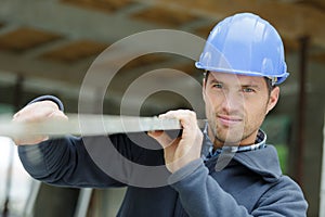 Contractor in hard hat holding plank wood