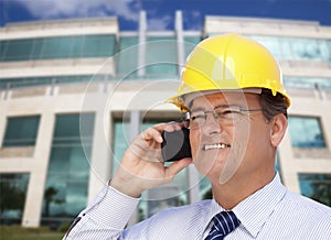 Contractor in Hardhat Talks on Phone In Front of Building