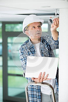 Contractor holding laptop and surveillance camera