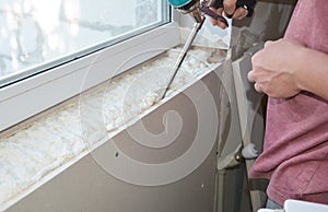 Contractor install and insulate house window sill with caulcing gun photo