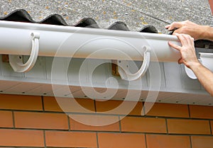 Contractor installing plastic roof gutter. Plastic Guttering, Rain Guttering & Drainage by Handyman hands