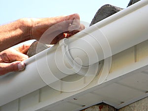 Contractor installing plastic roof gutter. Plastic Roof Guttering Renovation, Rain Guttering Repair & Drainage