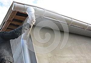 Contractor installing roof gutter downspout pipe.