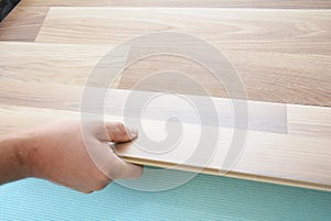 Contractor installing wooden laminate flooring with insulation and soundproofing sheets. Man laying laminate flooring.