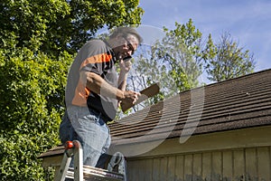 Contractor On Ladder Figuring Hail Damage Reairs To Roof