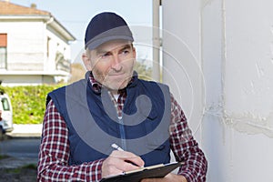 contractor making notes on clipboard while assessing exterior property