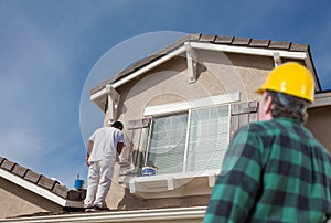 Contractor Overlooking Painter Painting House photo