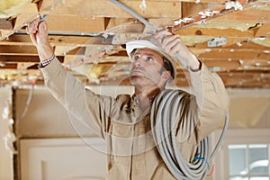 contractor passing cabling through roof timbers