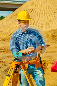 A contractor with theodolite writing in clipboard