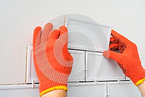 Contractor is tiling the white tiles on the kitchen wall. Concept of a kitchen renovation.