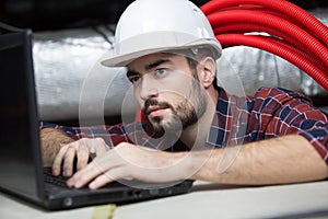 Contractor using laptop in roofspace