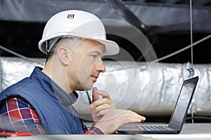 contractor using laptop in roofspace