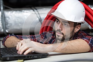 contractor using laptop in roofspace