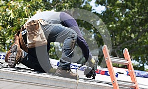 Contractor using nail gun replacing roof shingles on a roof