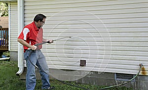 Contractor Using A Pressure Washer To Clean Vinyl Siding