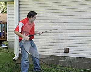 Contractor Using A Pressure Washer To Clean Vinyl Siding