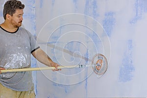 Contractor using sand trowel sanding the drywall