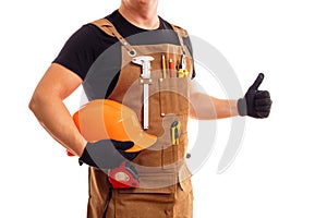 Contractor worker or carpenter in apron with tools and helmet holding thumbs up