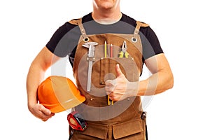 Contractor worker or carpenter in apron with tools and helmet holding thumbs up