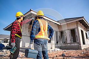 Contractor and worker holding electrician toolbox at unfinished house at construction site. Teamwork concept