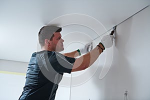 Contractor worker streching a stretch ceiling. Renovation and construction services