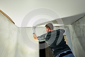 Contractor worker streching a stretch ceiling. Renovation and construction services