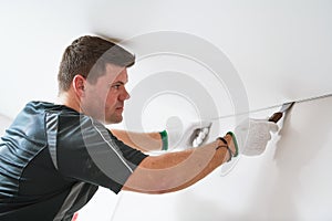 Contractor worker streching a stretch ceiling. Renovation and construction services