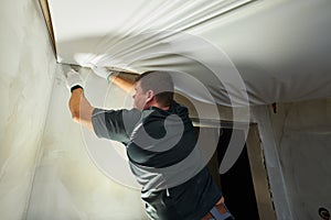 Contractor worker streching a stretch ceiling. Renovation and construction services