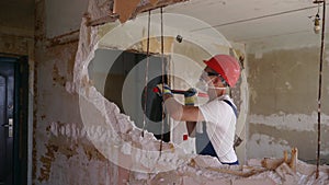 Contractor wrecks wall with sledgehammer making hole for rearrangement. Man doing manual dismantling and demolition