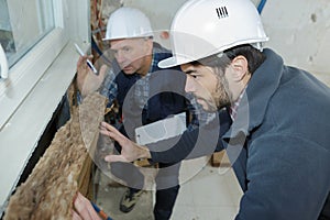 Contractors fitting insulation under window