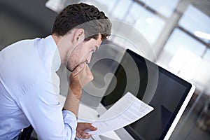 Contracts- always read the fine print. A young executive reviewing a contract while sitting at his desk.