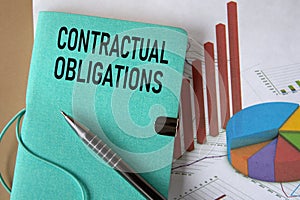 CONTRACTUAL OBLIGATIONS - words on a green piece of paper on the background of a chart and a pen