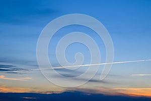 Contrail from airplane on a blue sky against a sunset