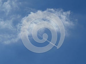 Contrail from jet engine of the airplane over the blue sky from the cloud