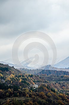 Contrast between autumn hills and snow covered high mountains