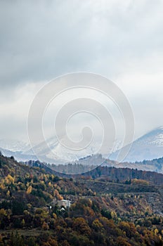 Contrast between autumn hills and snow covered high mountains