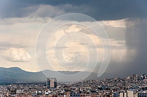 Contrast dark wall of falling water from the moody sky of the coming storm on the city. Panoramic cityscape view on Greece capital