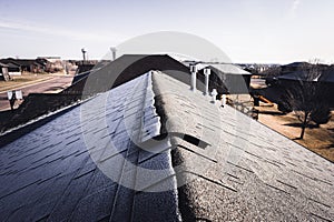 Contrast of frost line on a shingle roof as the sun rises and melts it