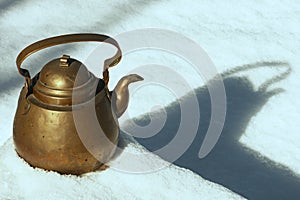 Copper teakettle set in snow with shadow and text space. photo