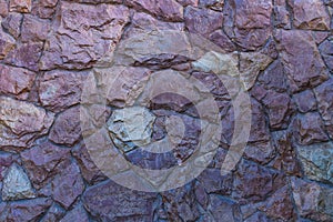 Contrast photo of a fragment of a wall made from raw rough varnished stone