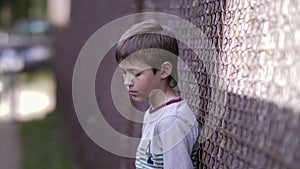 Contrasting Emotions: Sad Boy Stands on the Street and Gazes into the Camera, Remorseful Troublemaker Regrets His