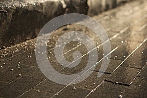 Contrasty filled frame background wallpaper photo of dark wet shiny tile with drops of rain and water, reflecting the rays of