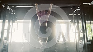 Contre-jour Aesthetic Shot: A Strong Woman Training with Pullups. Female Bodybuilder Doing Core