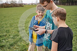The control panel is in the hands of the boy who controls the drone. Children control a flying quadcopter