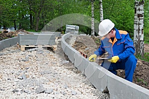 A control worker makes a measurement of the quality of the road construction course