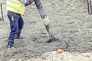 Contruction worker pouring concrete, directing the pump and working in foundation