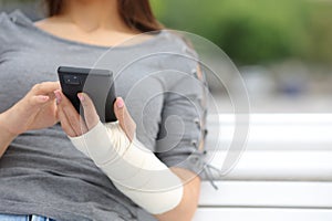 Convalescent woman with bandaged arm using phone photo