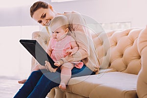 Emotional babysitter showing modern device to a child and smiling